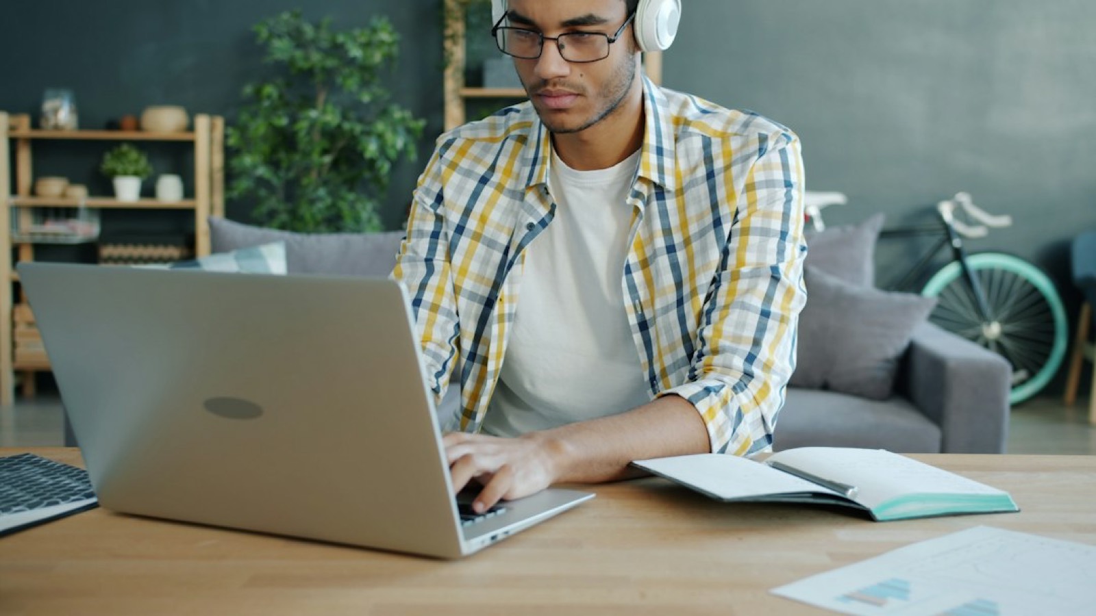 Personne apprenant une langue avec un casque audio et un carnet sur un bureau