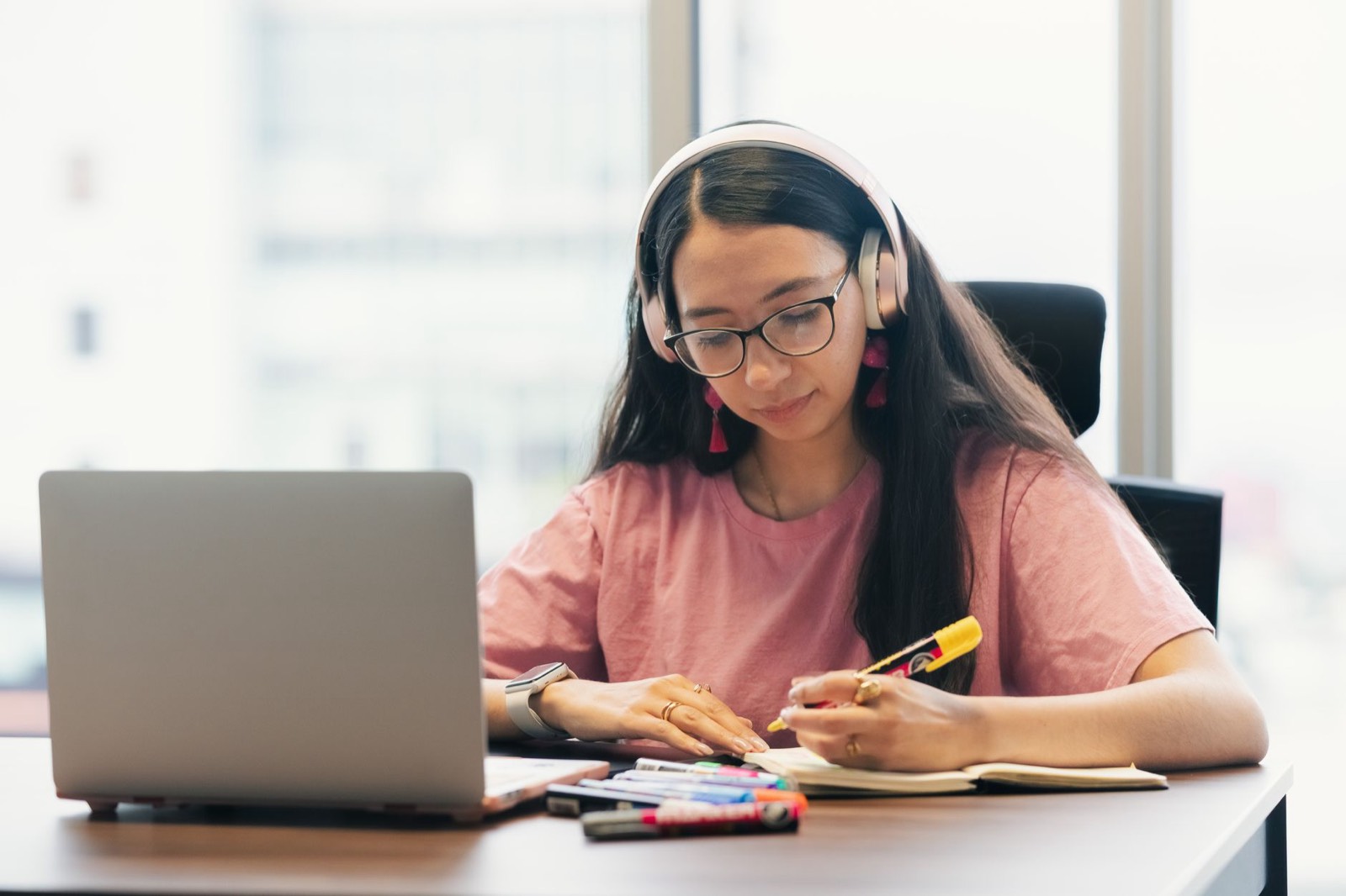 Personne apprenant une langue avec un casque, un cahier et un smartphone sur un bureau