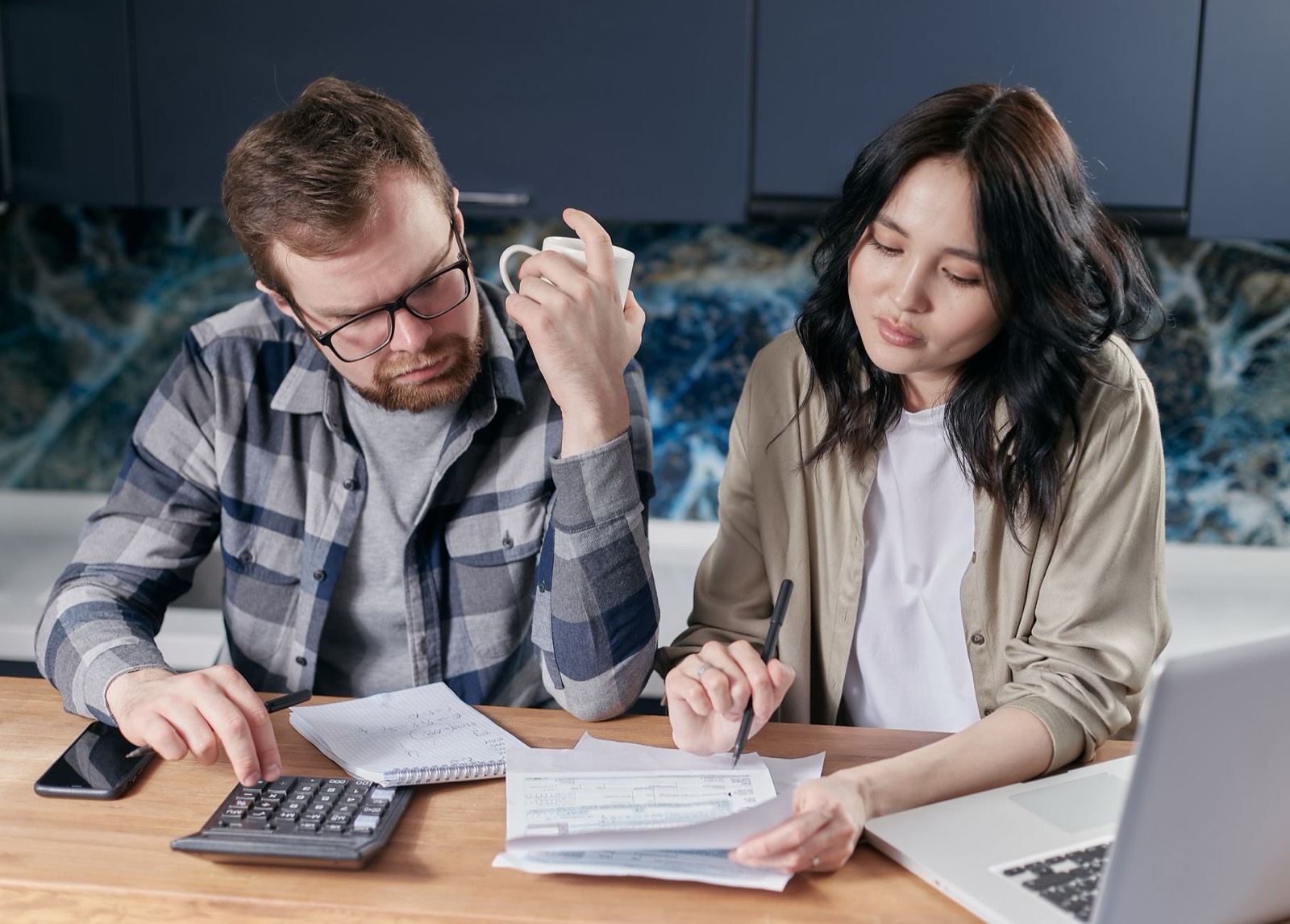 Budget du foyer et factures posées sur une table, calculatrice à côté